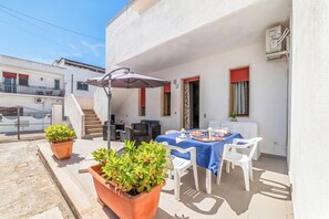 An outdoor patio with a table set for dining, surrounded by potted plants and white chairs. - Leuca Relax&Sea n.1C, Castrignano del Capo, Italy (Castrignano del Capo)