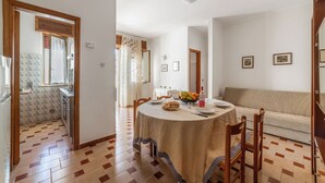 Un comedor con una mesa redonda, sillas, un sofá y una cocina al fondo.