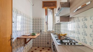 Cocina compacta con baldosas estampadas, encimera de madera, estufa a gas y una ventana con cortinas.