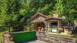 Una cabana rústica de fusta amb una xemeneia de pedra, envoltada per un bosc dens.