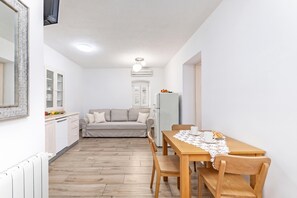 Un espacio habitable compacto con kitchenette, un sofá, una mesa de comedor con sillas y un refrigerador.