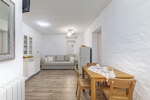 Un espacio habitable compacto con kitchenette, comedor y sofá.