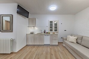A compact kitchen with white cabinets, a built-in oven, and a dining area with a sofa. - Lovrinovi Retreat - Apartment 2, Zvoneća, Croatia (Zvoneća)