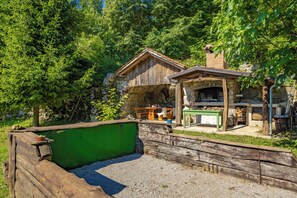 A rustic wooden cabin with a stone chimney, a green outdoor seating area, and a stone wall. - Nature & Pool Escape - Stone House, Zvoneća, Croatia (Zvoneća)