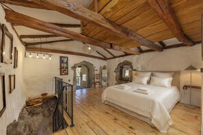 A rustic bedroom with a wooden ceiling, a bed with white linens, a stone wall, and a staircase. - Stone House Lovrinovi Shared Pool, Zvoneća, Croatia (Zvoneća)
