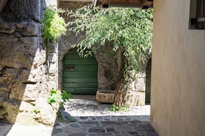 A stone archway leading to a green door, surrounded by stone walls and a small tree. - Lovrinovi Retreat - Apartment 1, Zvoneća, Croatia (Zvoneća)