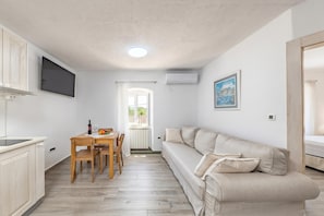 Un espacio habitable compacto con kitchenette, comedor, sofá y vistas a través de una ventana.