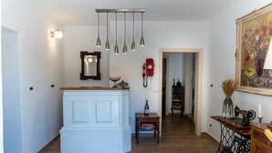 Une pièce avec un meuble blanc, des lampes suspendues, un téléphone à cadran rouge, un tableau encadré et une machine à coudre posée sur une table en bois.