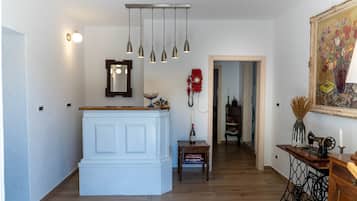 Une pièce avec un meuble blanc, des lampes suspendues, un téléphone à cadran rouge, un tableau encadré et une machine à coudre posée sur une table en bois.