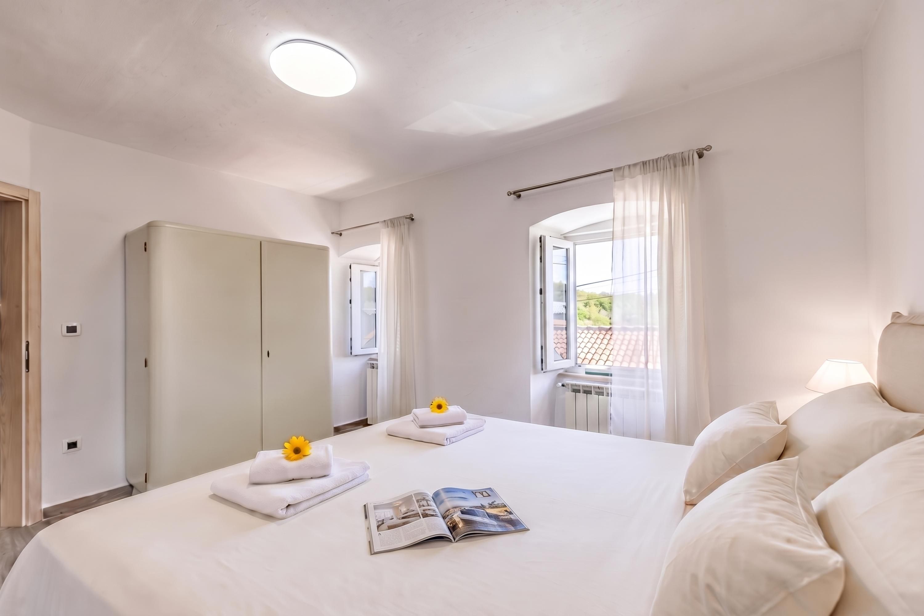 A hotel room with a bed, a wardrobe, a window with curtains, and a radiator.
