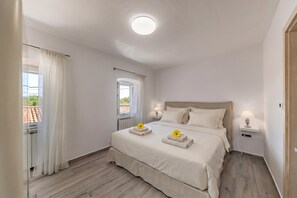 A bedroom with a bed, two bedside tables, a window with curtains, and a view of the outside. - Lovrinovi Retreat - Apartment 1, Zvoneća, Croatia (Zvoneća)