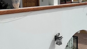 A building with a white facade, a wooden door, a window, and a potted plant. - HOTEL CUADRA CASONA EL CALVARIO (Huichapan)