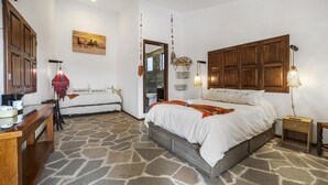 A bedroom with a stone floor, wooden bed frame, bedside tables, and a wardrobe. - HOTEL CUADRA CASONA EL CALVARIO (Huichapan)