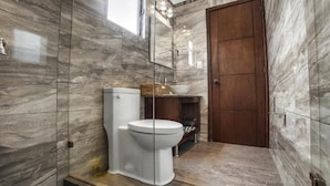 A bathroom with a toilet, a sink, a mirror, and a wooden door. - HOTEL CUADRA CASONA EL CALVARIO (Huichapan)