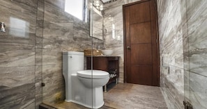 Ein Badezimmer mit Toilette, Waschbecken, Spiegel und Holztür.