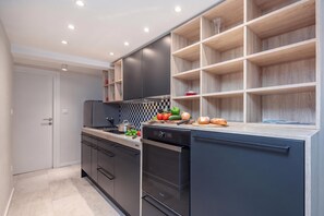 A modern kitchen with dark cabinetry, a checkered backsplash, and a variety of fresh produce on the counter. - Casa del Porto Seafront Apartment, Moščenićka draga, Croatia (Moščenićka draga)
