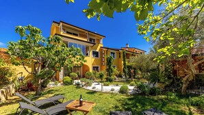 Ein gelbes, zweistöckiges Haus mit gepflegtem Garten, Außenbereich und blauem Himmel.