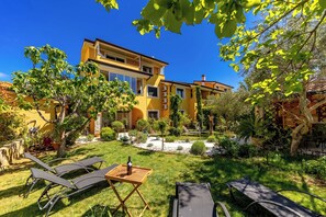 Ein gelbes, zweistöckiges Haus mit gepflegtem Garten, Außenbereich und blauem Himmel.