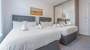 Een hotelkamer met twee bedden, een grote spiegel en kunstwerken aan de muur.
