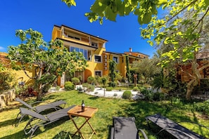Ein gelbes, zweistöckiges Haus mit gepflegtem Garten, Außenbereich und blauem Himmel.
