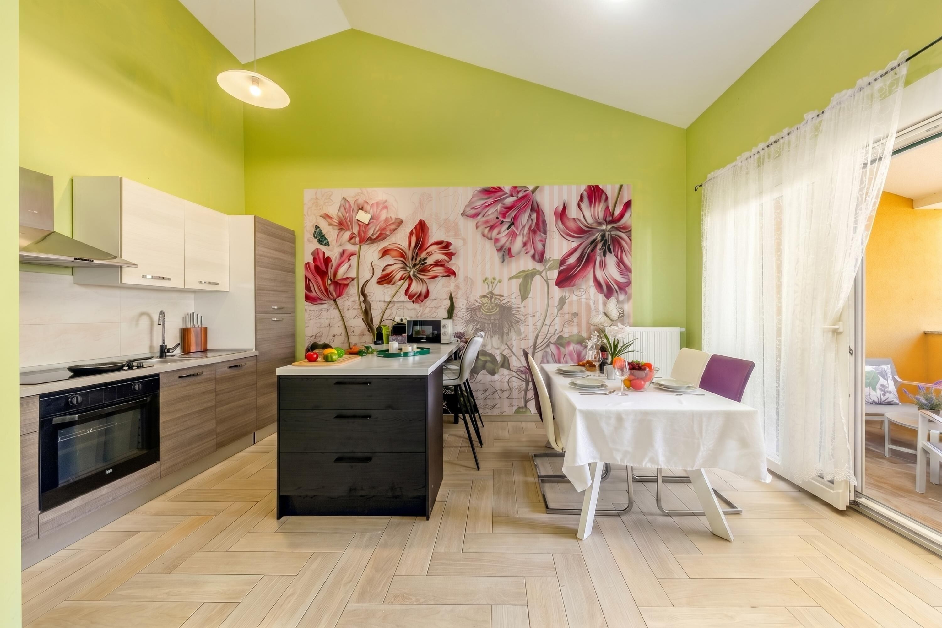 Cozinha moderna com área de refeições, apresentando um grande mural floral, uma mesa de jantar e uma ilha de cozinha.