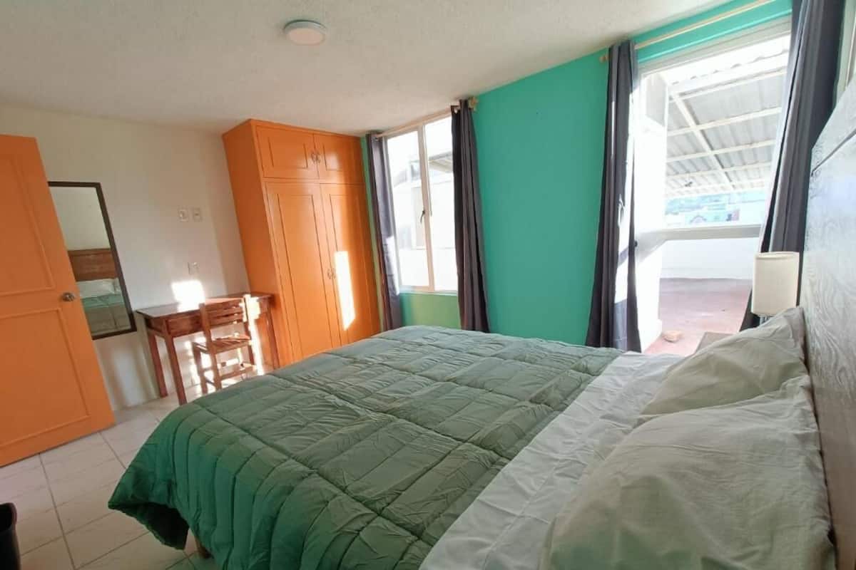 Un dormitorio con cama, escritorio y armario.