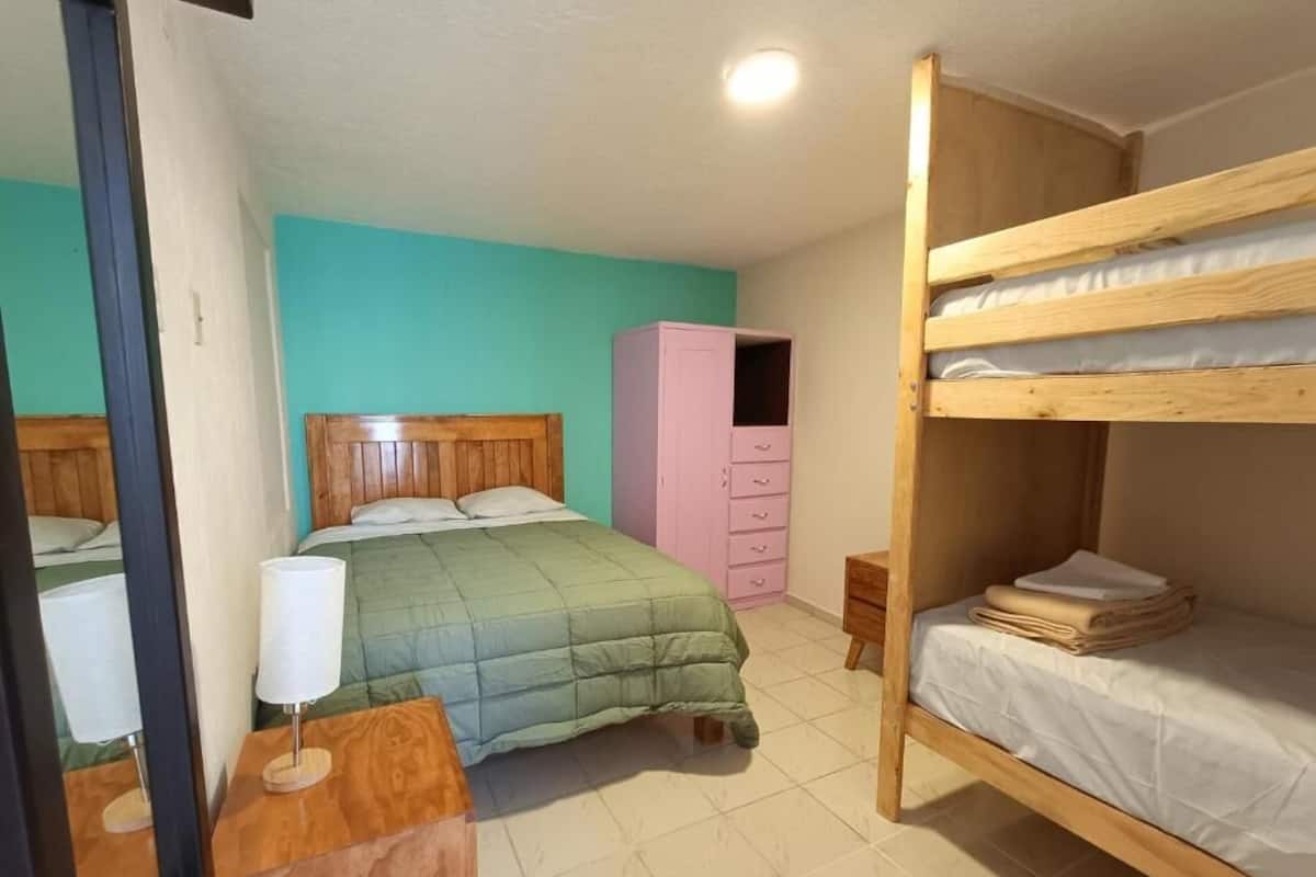 Un dormitorio con una cama litera, una cama individual, un aparador y un armario.