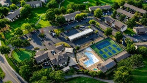 Vista aerea di una zona residenziale con case, una piscina, campi da tennis e un campo da golf.
