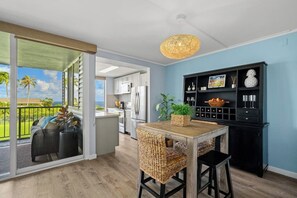 Une cuisine moderne avec un coin repas, une bibliothèque noire et une vue sur l’extérieur.