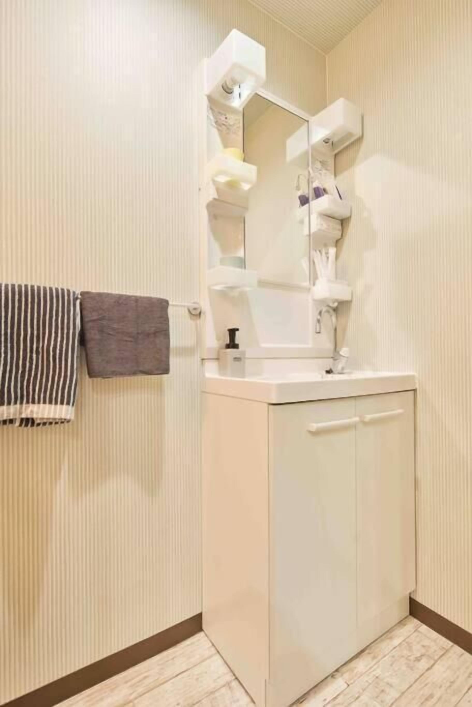 A bathroom with a white cabinet, a mirror, and a towel rack.