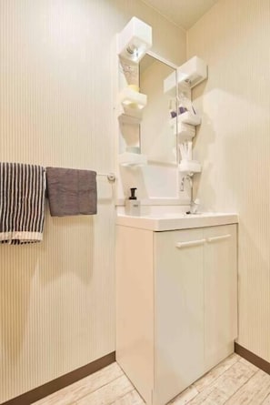 Ein Badezimmer mit einem weißen Schrank, einem Spiegel und einem Handtuchhalter.