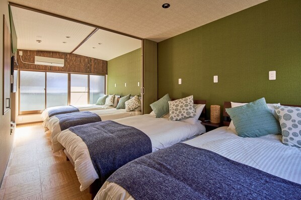 A hotel room with three beds, a large window, and a view of the sea. - Nishikucho Modern Residence (Osaka)
