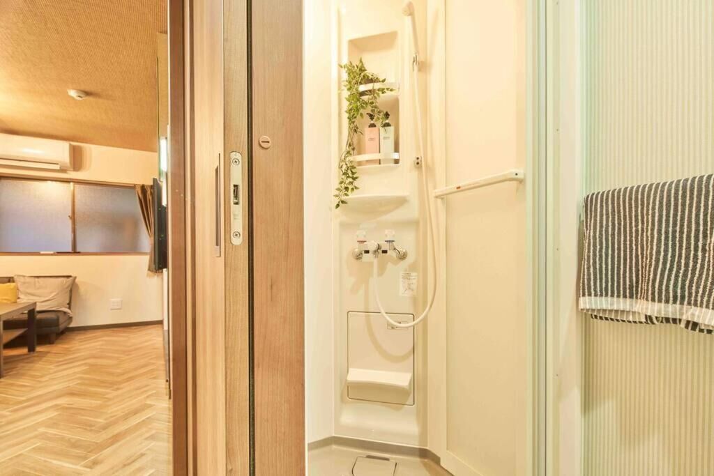 A modern bathroom with a shower, a towel rack, and a small shelf with toiletries.