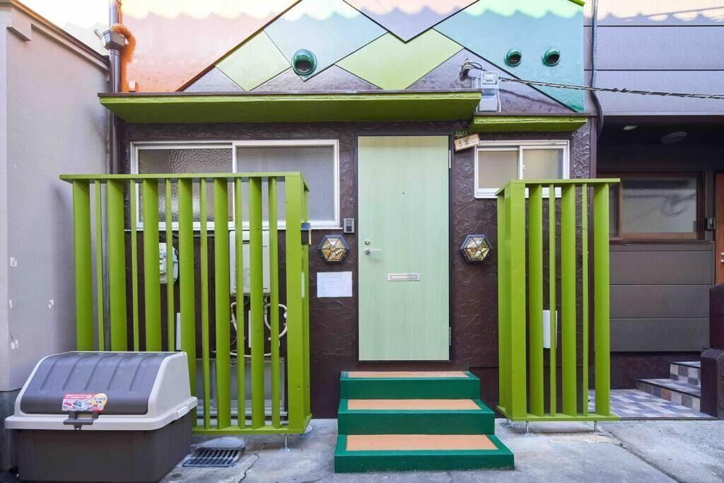 Een gebouw met een groene poort, een lichtgroene deur en een trap naar de ingang.