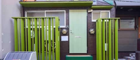 A building with a green gate, a light green door, and steps leading to the entrance.