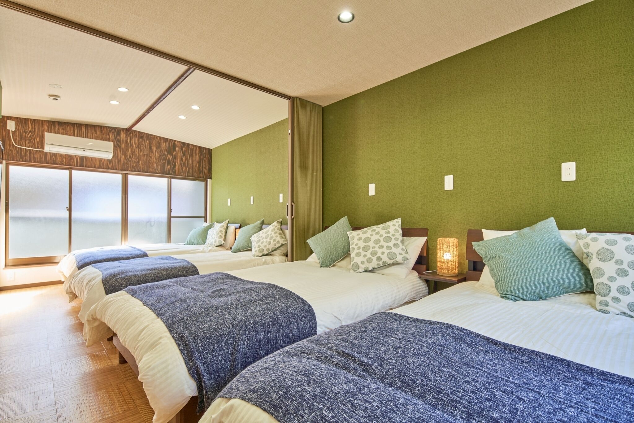A hotel room with four beds, a large window, and an air conditioning unit.