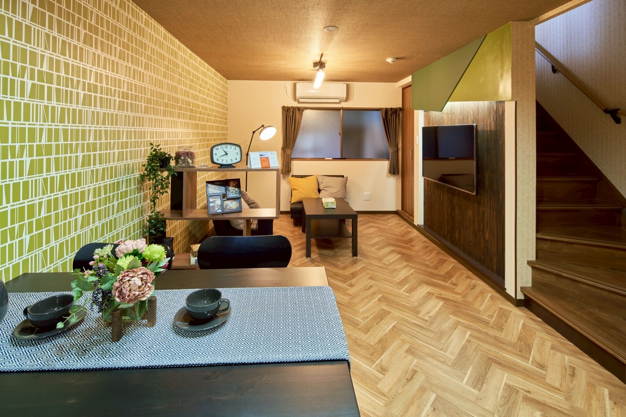 A compact living space with a dining area, kitchenette, and a staircase.