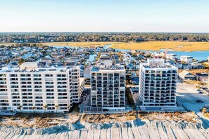 A coastal residential area with modern apartment buildings, a marina, and a beach in the background. - Oceanfront condo with spacious private balcony, pool & direct beach access (North Myrtle Beach)