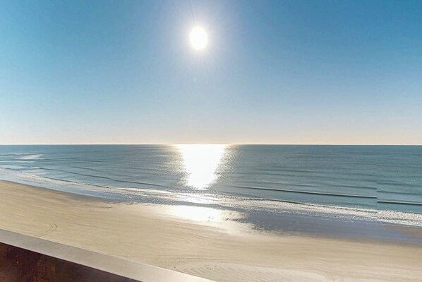 A beach with a clear sky and calm sea. - Oceanfront condo with spacious private balcony, pool & direct beach access (North Myrtle Beach)