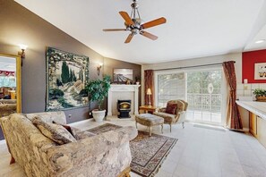 A living room with a fireplace, a ceiling fan, and a large painting on the wall. - Family friendly house w/ pool table - access to a shared pool and tennis court (Groveland)