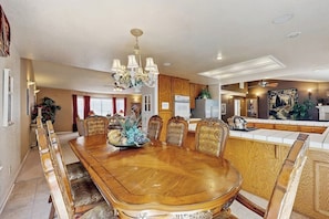 A dining area with a large wooden table, ornate chairs, a chandelier, and a kitchen in the background. - Family friendly house w/ pool table - access to a shared pool and tennis court (Groveland)