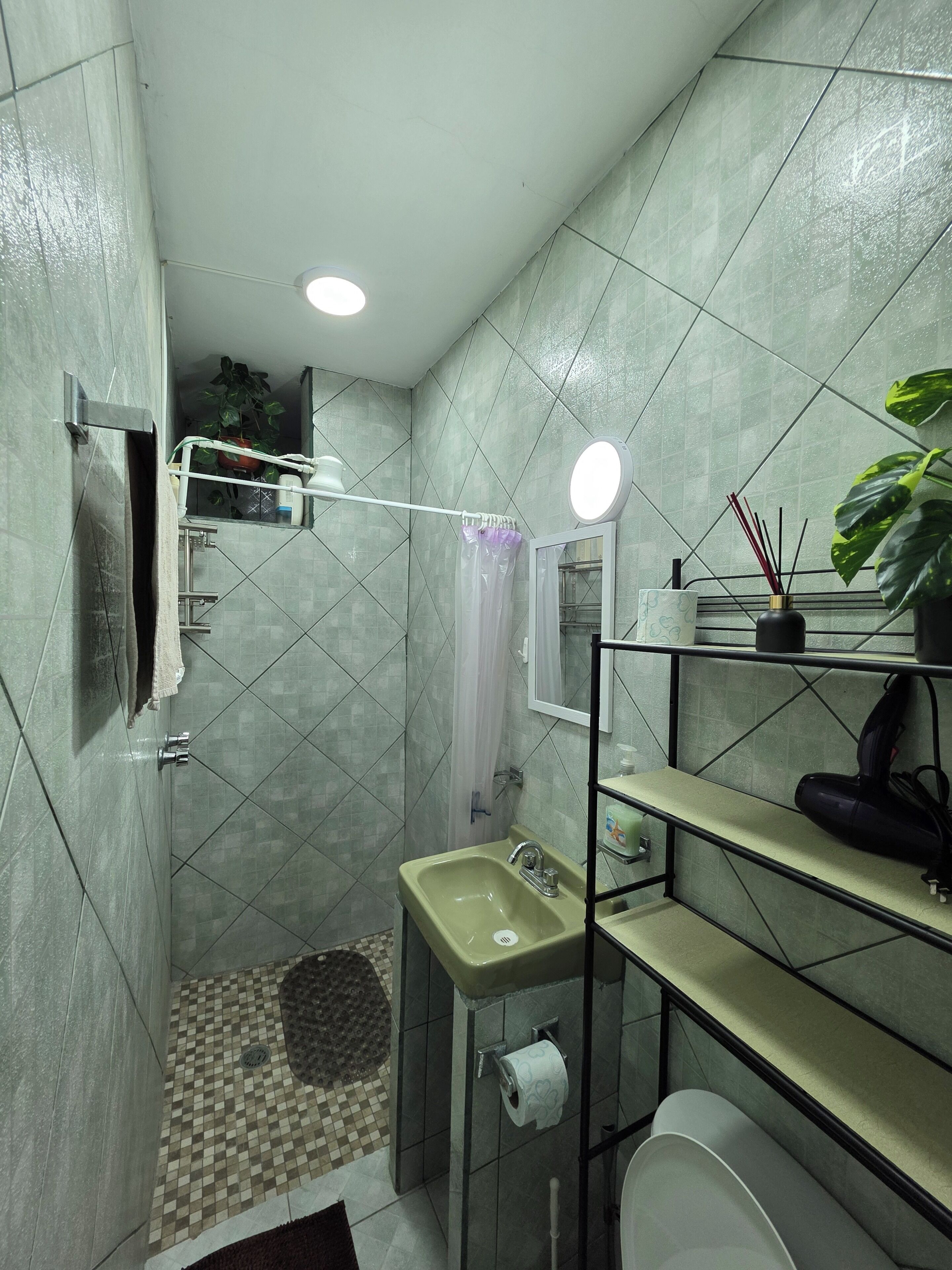 Un baño con ducha, lavamanos, inodoro y espejo.