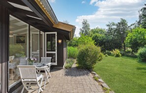 A patio with outdoor seating, a pathway leading to a grassy area, and a wooden structure with glass doors. - Lovely home in Vejby with WiFi (Vejby)