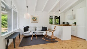 A modern interior with a sofa, rocking chair, dining table, kitchen area, and large windows. - Lovely home in Vejby with WiFi (Vejby)