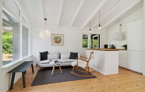 A modern interior with a sofa, rocking chair, dining table, kitchen area, and large windows. - Lovely home in Vejby with WiFi (Vejby)