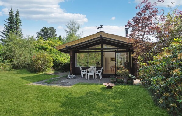 A modern house with a glass-enclosed patio, white chairs, and a small table. - Lovely home in Vejby with WiFi (Vejby)