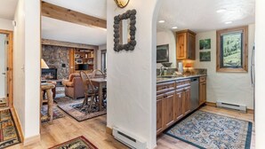 Ein gemütliches Interieur mit Kamin aus Stein, Holzmöbeln und einer Küche mit Holzausstattung und einem Fenster.