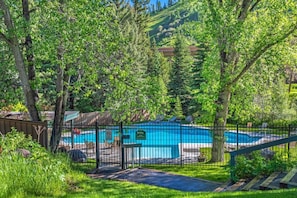 Ein Garten mit Swimmingpool, umgeben von Bäumen und einem Zaun.