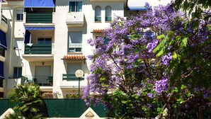 Un immeuble à plusieurs étages, doté de balcons, d’une façade blanche et d’une clôture verte.