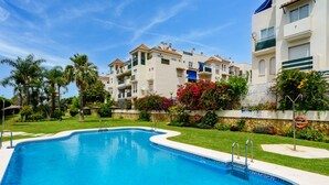 Une piscine à bord incurvé, entourée d’une pelouse bien entretenue et de palmiers.